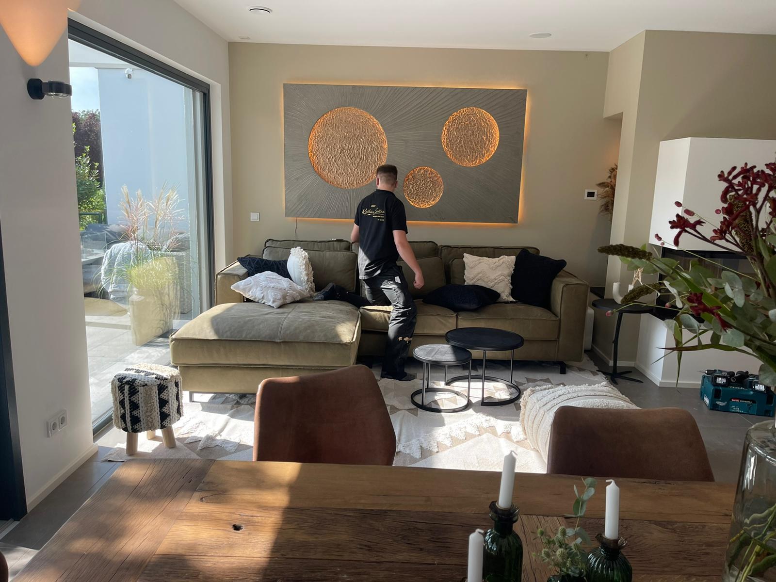 Montage im Wohnzimmer: ein Mitarbeiter des Ateliers am fertig aufgehängten Werk