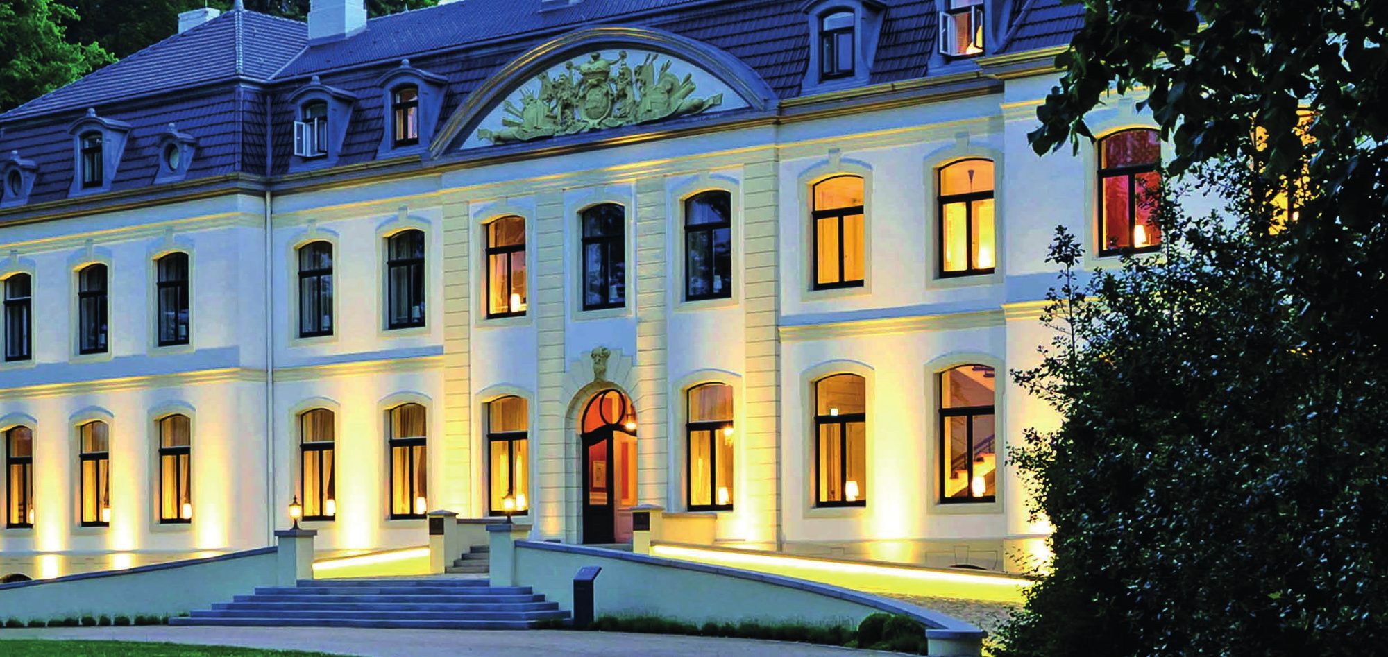 Das beleuchtete Schloss Weissenhaus am Abend, Blick auf die Freitreppe und die Fassade.